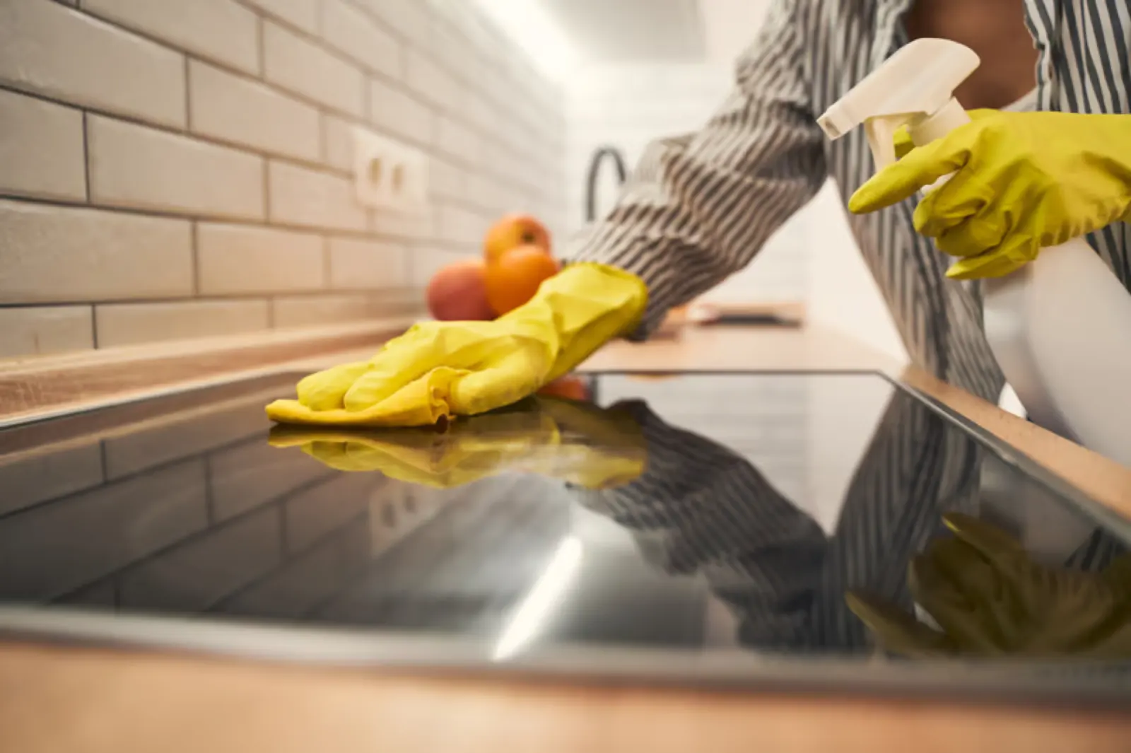 Close-up of a kitchen cooktop being wiped down during a detailed home cleaning
